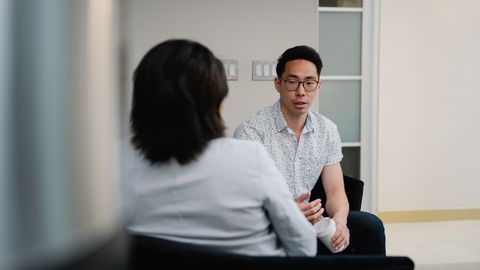 Two colleagues having a focused conversation in an office setting.