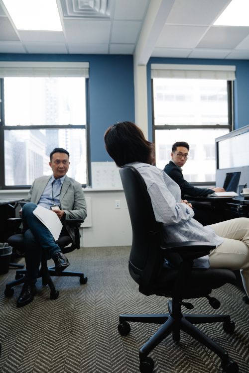 Free Three professionals discussing in a modern office setting with natural daylight. Stock Photo