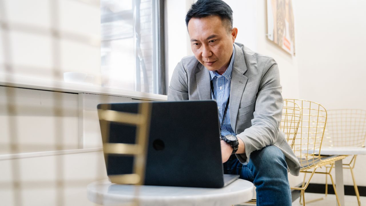 Man working on a laptop in a bright, modern office setting, focusing on tasks.