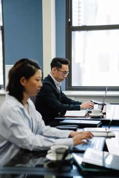 Two business professionals focused on laptops in a modern office setting.