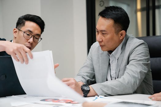 Two professional men engaged in a focused discussion in a contemporary office environment.