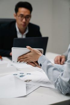 Professionals working with a digital tablet and documents in a modern office setting.