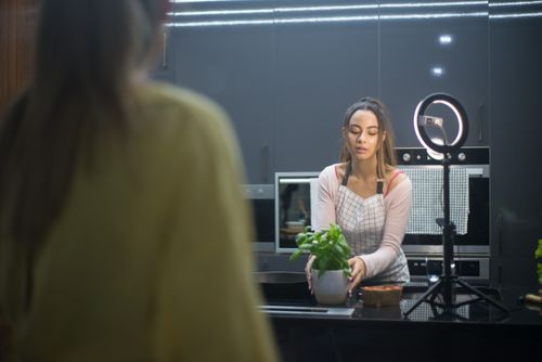Free A woman arranging a potted plant on a kitchen counter, set for content creation. Stock Photo