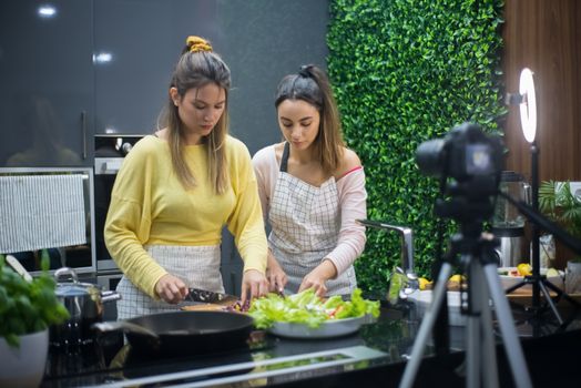 Two women preparing a fresh salad together in a modern kitchen.