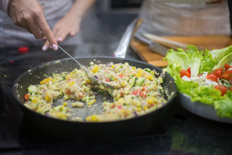 A Hand Cooking On A Frying Pan