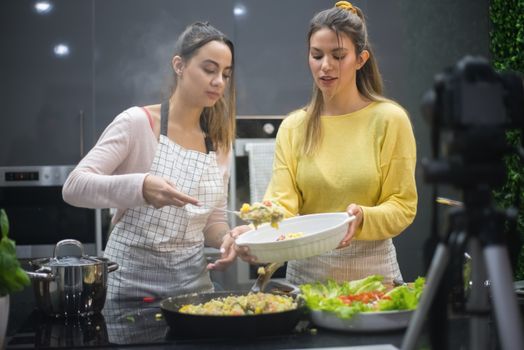 Two women prepare a delicious meal in a stylish kitchen, showcasing food preparation and culinary skills.