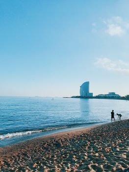 Sunny beach scene at Barcelona seafront featuring the W Hotel in the distance.