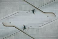 这栋时尚的现代建筑具有有趣的反射对称性，楼梯上有一个孤独的男人在行走