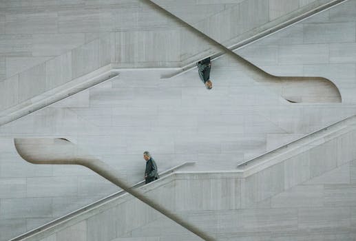 这栋时尚的现代建筑具有有趣的反射对称性，楼梯上有一个孤独的男人在行走