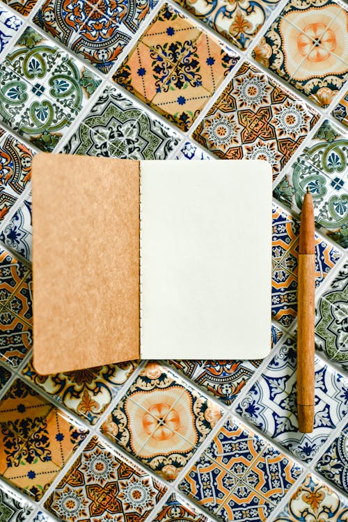 A Notebook and Wooden Pen on Tile Flooring