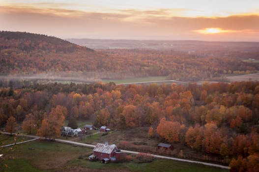 从空中俯瞰风景如画的乡村，可以看到秋叶和日落时分的农舍