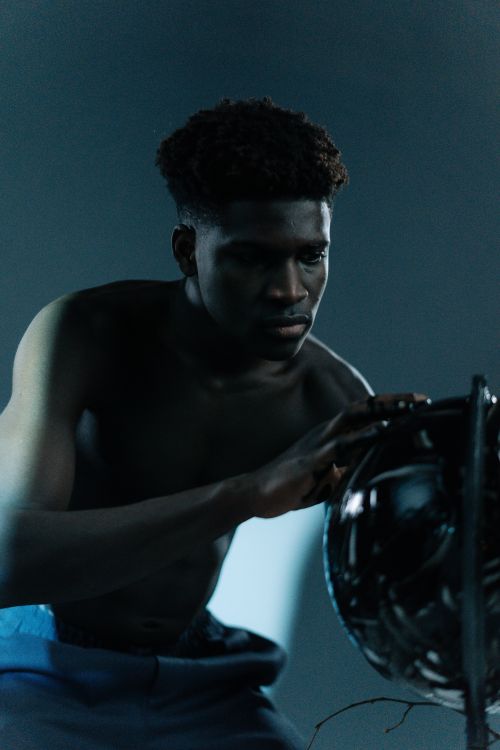 Free Moody studio portrait featuring a muscular, shirtless man engaging with a dark lantern. Stock Photo