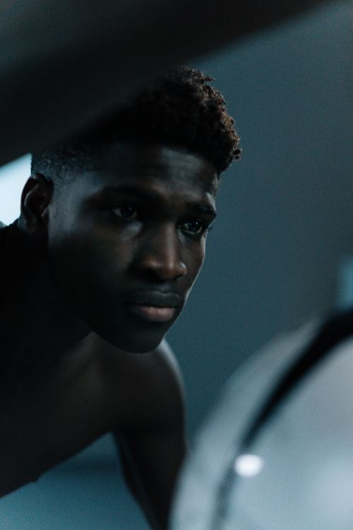 Free Close-up portrait of a thoughtful man with afro hairstyle in subdued lighting, looking away. Stock Photo