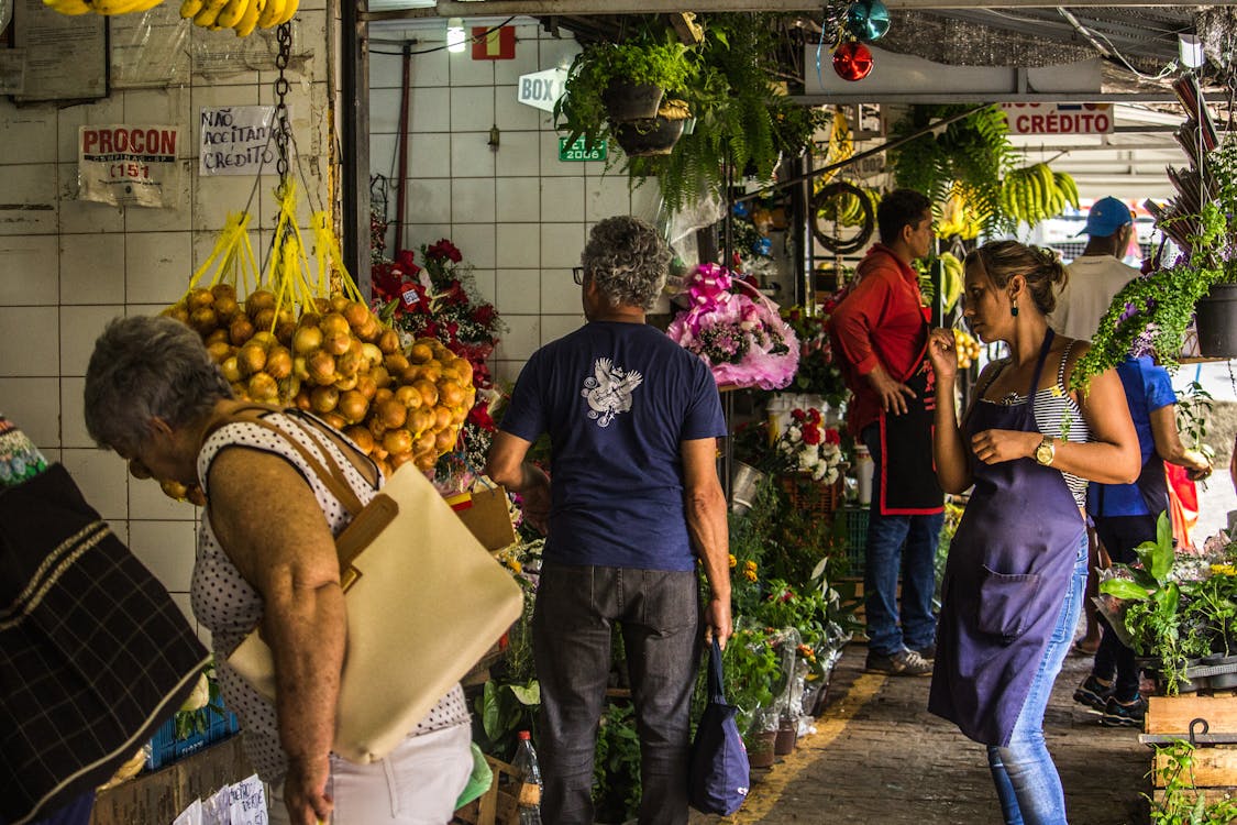buyers and sellers Standing on Grey Concrete Surface Surrounded With a Plants and Vegetables market