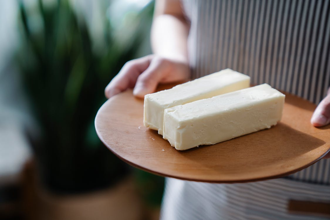 Free Close-Up Shot of a Person Holding a Wooden Plate with Sliced Butters Stock Photo