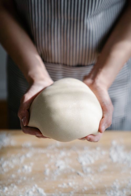 Free A person kneading fresh bread dough on a floured surface, wearing an apron. Stock Photo