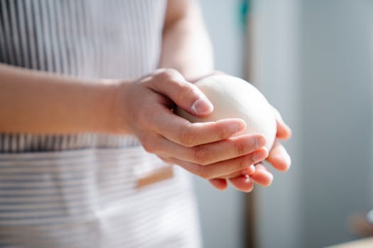 Close-up of a person shaping dough, showcasing hands-on cooking in a kitchen setting.