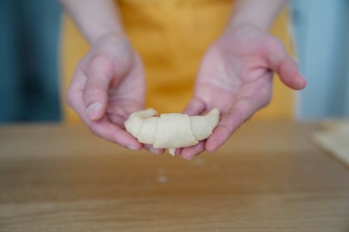 Free Close-up of a person holding croissant dough, preparing for baking. Stock Photo