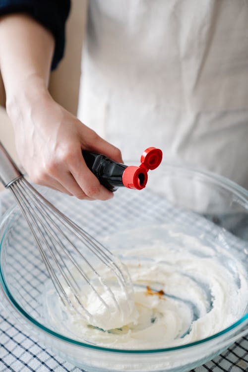 Woman Adding Vanilla Extract to the Cream 