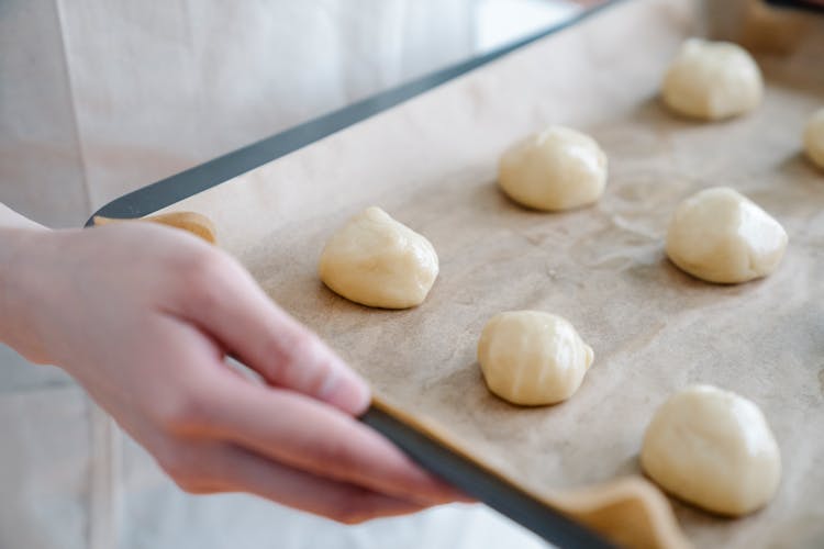 Woman Holding A Baking Sheet With Raw Buns 