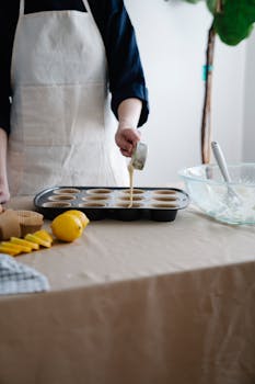Person preparing lemon muffins in a home kitchen setting.