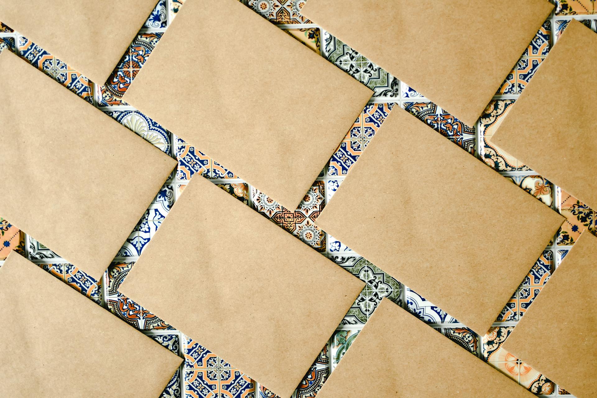 Brown envelopes overlay a vibrant tiled pattern, creating a textured design effect.