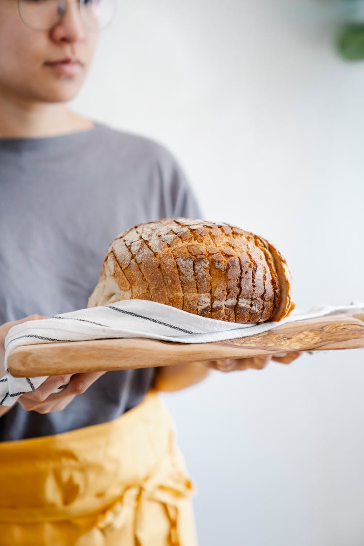 Woman Holding Bread On Cutting Board