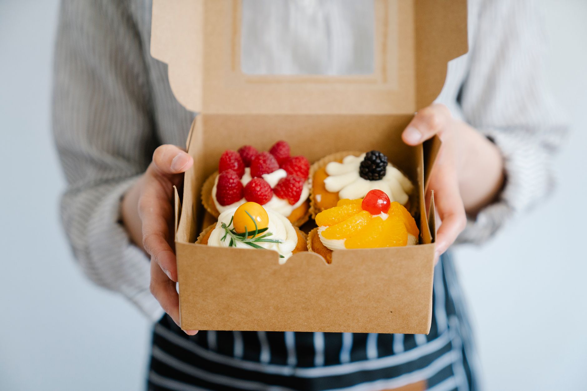 Chef adding ingredients to boxed cake mix batter in a white bowl