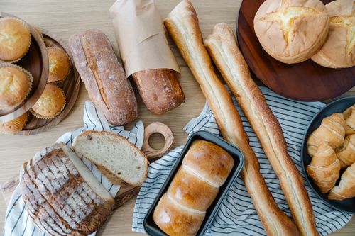 Free Top view of freshly baked bread and pastries on a wooden table, perfect for breakfast and culinary photography. Stock Photo