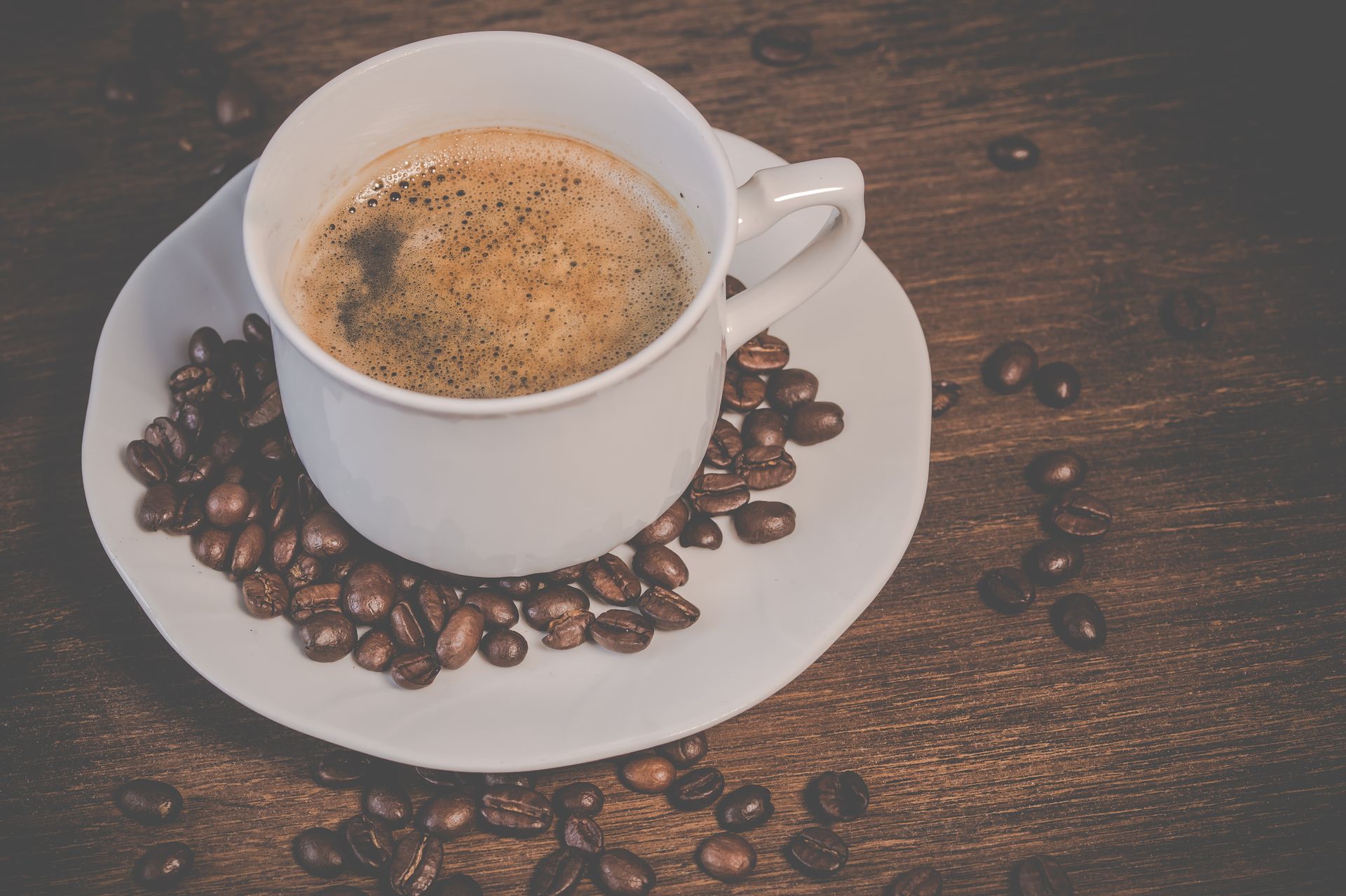 Taza de café humeante rodeada de granos de café