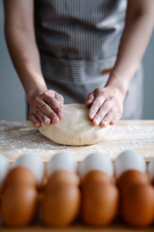 Free Close-up of hands kneading dough on a floured board with eggs. Stock Photo