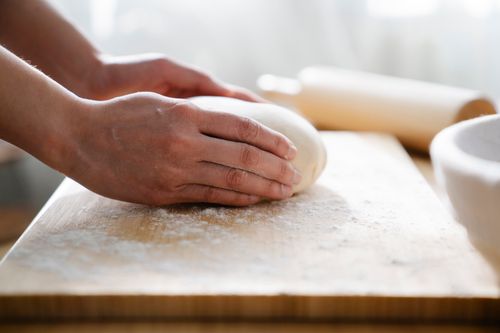Free Close-up of hands kneading dough on a floured wooden board, perfect for baking themes. Stock Photo