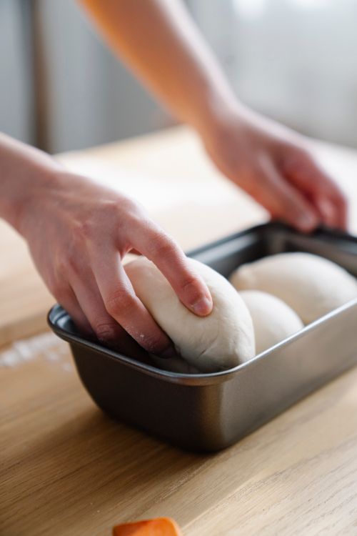Free Close-up of hands shaping dough in a baking pan, preparing homemade bread. Stock Photo