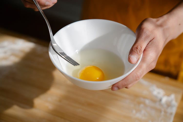 Person Holding Bowl Of Fresh Egg And Fork