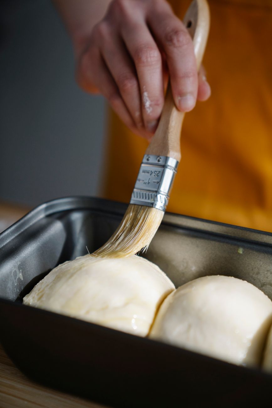 A baker brushing dough by hand