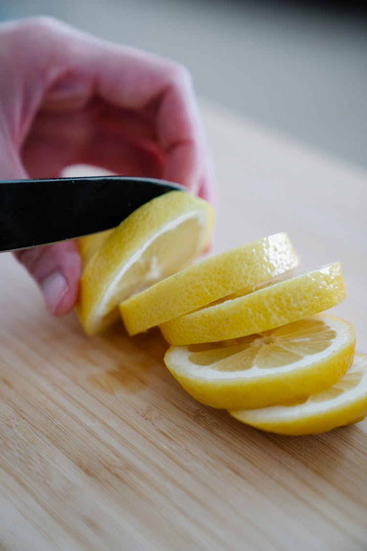 Person Slicing Lemon On A Cutting Board 