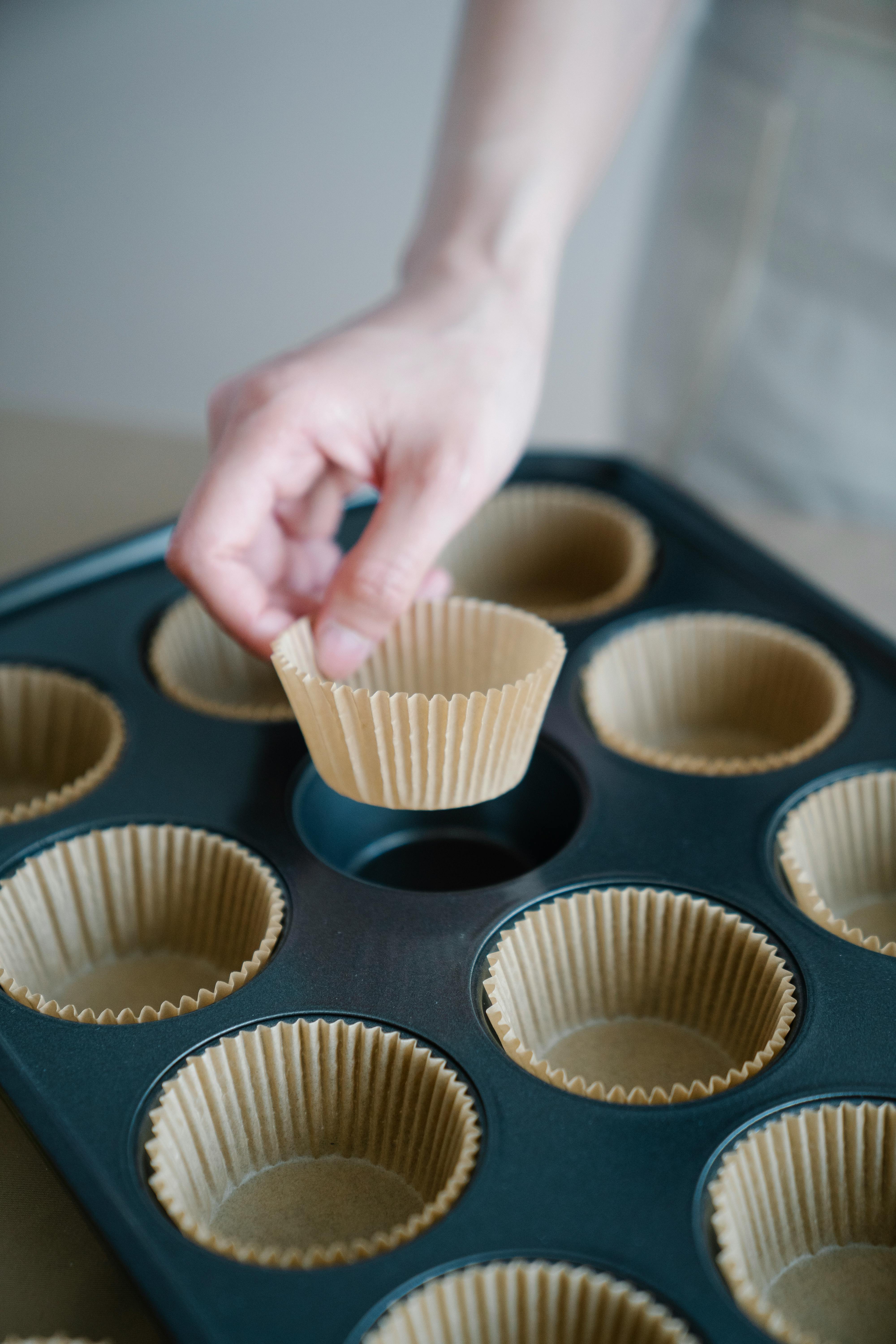 Cookie sheets, and cup muffin pan with paper liners close up on light  wooden background, flat lay Stock Photo - Alamy