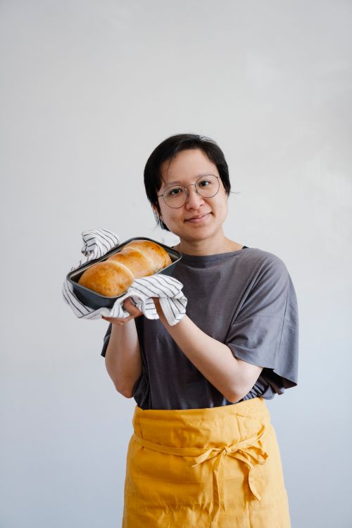 Free Portrait of a smiling baker showing off freshly baked bread in a tin tray. Stock Photo