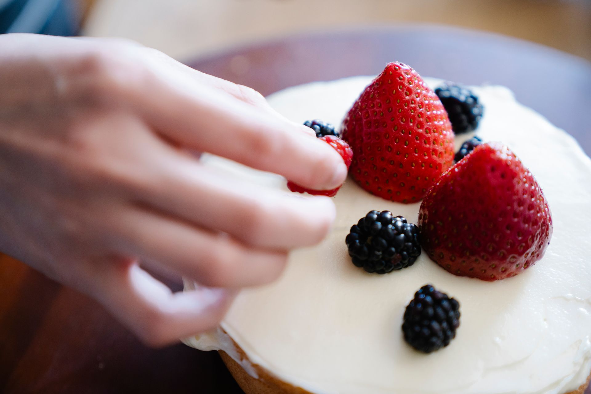 Person Putting Fresh Fruits on a Cake