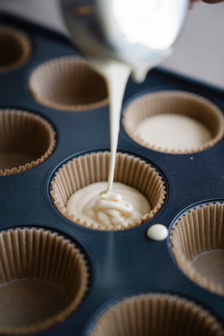 Person Pouring Batter In A Cupcake Liner