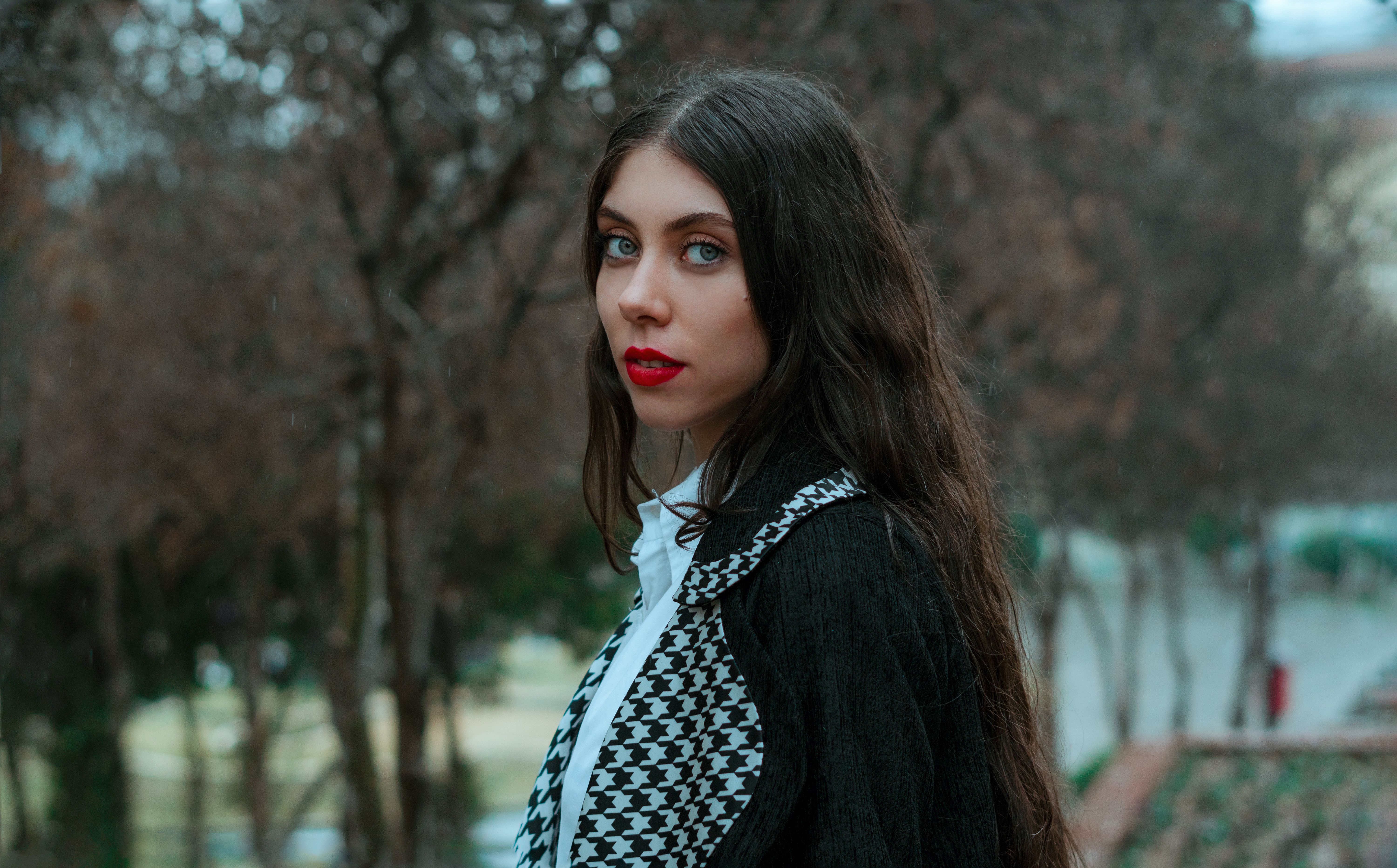 Stylish portrait of a woman outdoors with an autumnal background.