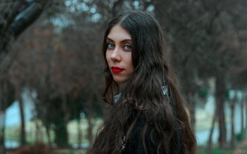 Portrait of a Woman in Red Lipstick and Trees in Background