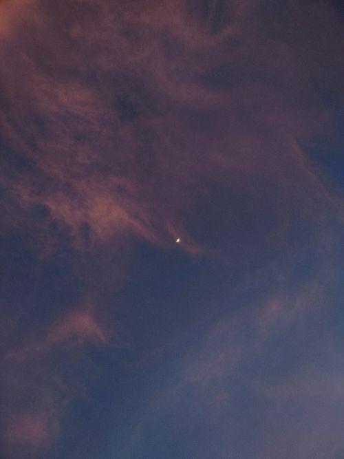 Free A serene sky with a crescent moon and soft pink clouds at dusk. Stock Photo