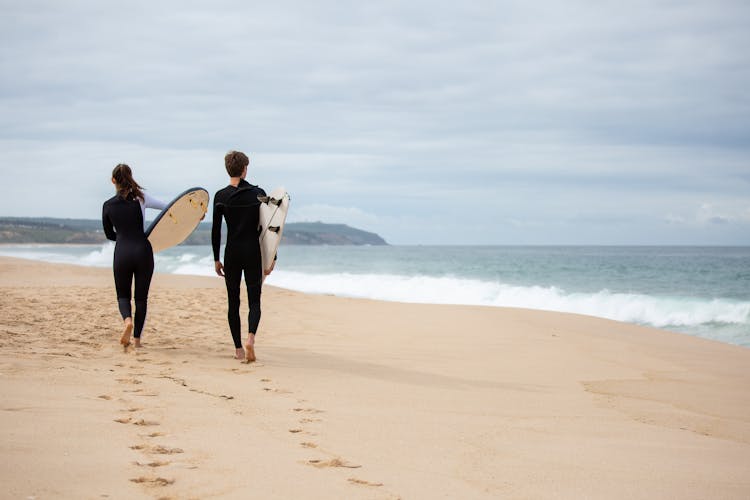 Back View Of Surfers With Their Surfboards