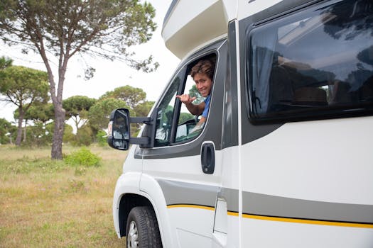 Smiling man driving a camper van through scenic countryside in Portugal, enjoying the adventure.