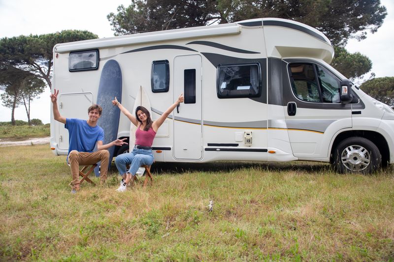 Pareja saludando junto a su autocaravana recién aparcada