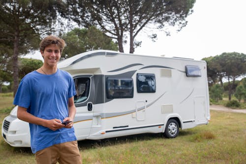 Man in Blue T-Shirt Standing by a White Camper Van