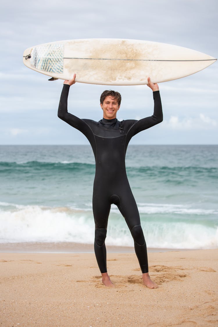 Man In Black Wetsuit Holding White Surfboard