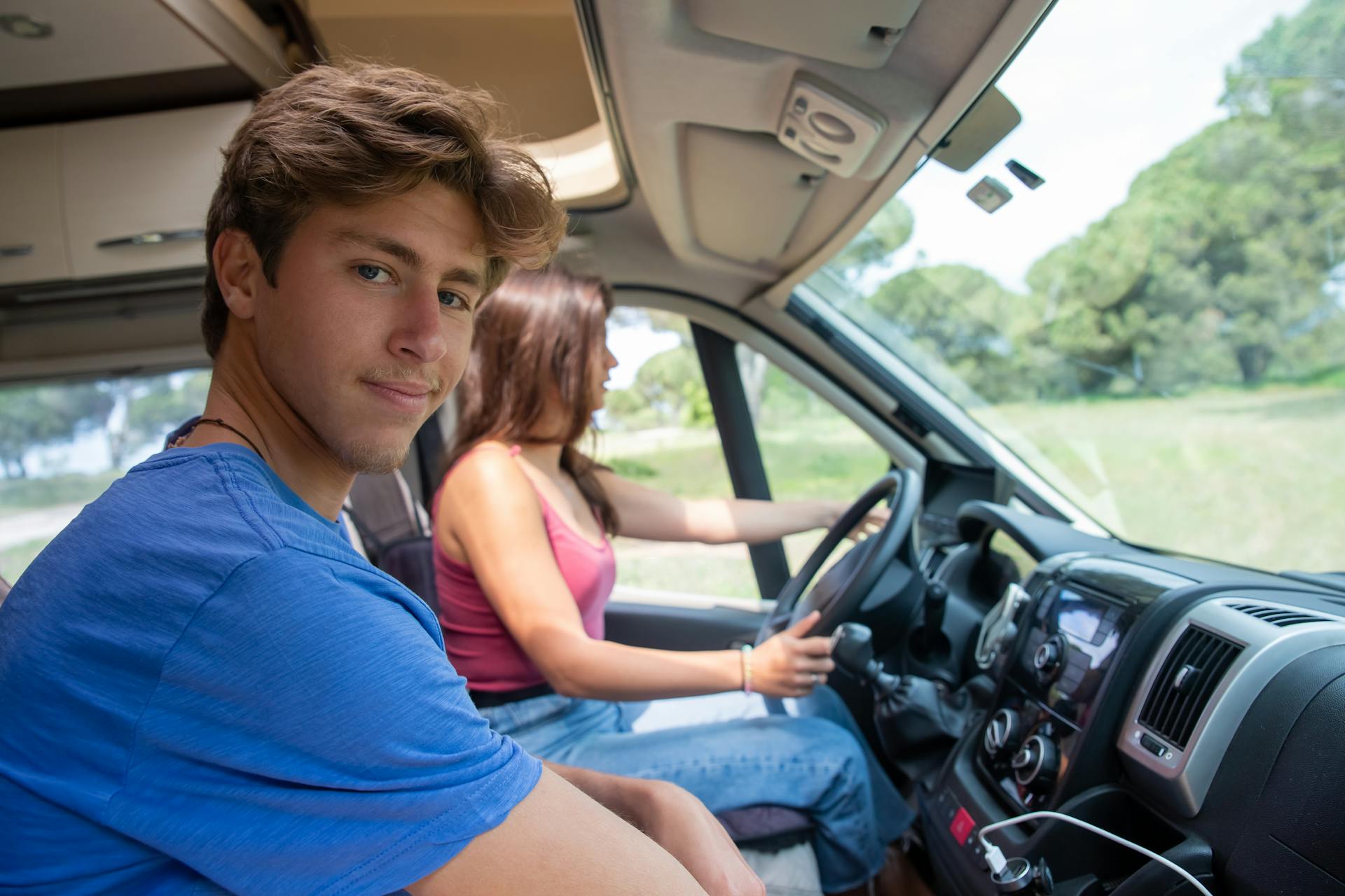 Young couple in an RV on a scenic road trip in Portugal, exploring nature.