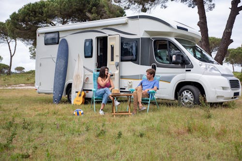 Free Man and Woman Sitting Beside  a Camper Stock Photo